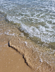 It is a sandy beach with waves rolling in.