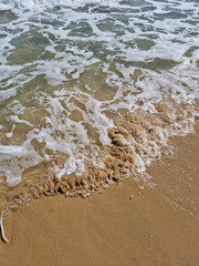 It is a sandy beach with waves rolling in.