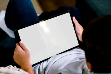 Boy holding a tablet computer with blank screen for mockup. White screen for place your design.