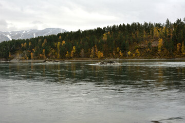 Rocky formations in the middle of a wide channel of a beautiful mountain river flowing through a...