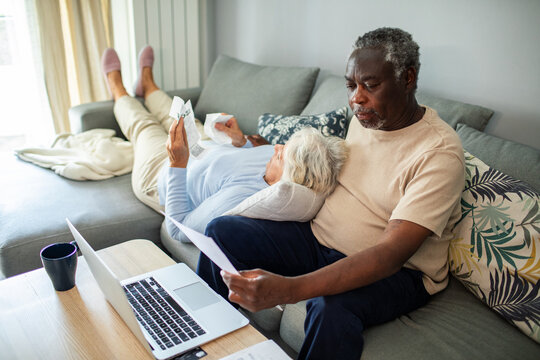 Diverse senior couple reading bills on the couch at home