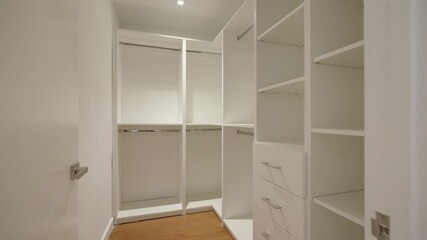 Well-lighted wardrobe with open doors, revealing shelves, drawers and hanging space. White and organized cabinet with clean and minimalist design