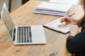 Analyzing the Data: A businesswoman's hand guides a pen across a pie chart, her focus unwavering as...