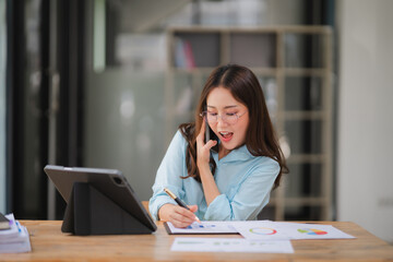 Unexpected Business Success: An Asian businesswoman reacts with surprise and joy during a phone...