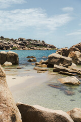 White sand beach with blue water surrounds by rocks
