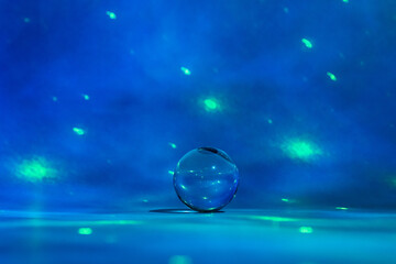 Glass ball surrounded by shades of blue with green light spots.