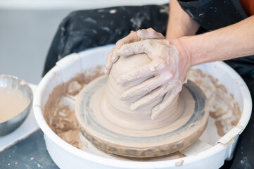 Close-up of a potter's hands working on a pottery wheel. 