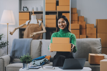 Asian SME business women use laptop computer checking customer order online shipping boxes at home....