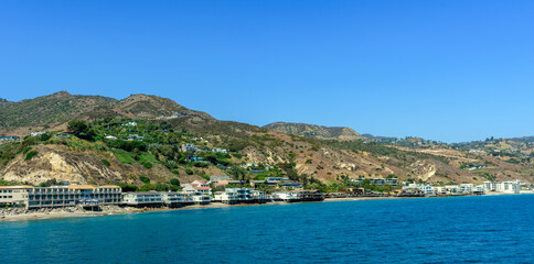 Panoramic scenic view from Malibu Pier overlooking Malibu's oceanfront properties, rugged hillsides, coastline and blue waters of Pacific ocean.