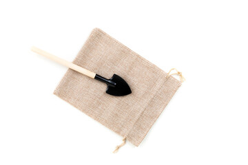 Toy gardening shovel on a canvas cinch bag isolated over white