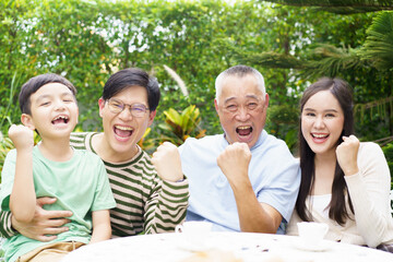 Multi generation Asian family relaxing in backyard garden together.