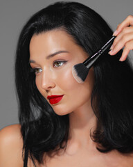 Elegant Woman with Red Lips Applying Makeup Using Brush in Beauty Shot