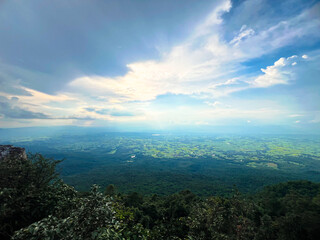 Panoramic view of lush green fields under a dramatic sky with sunlight breaking through the clouds. Perfect for landscape photography, nature themes, and environmental projects