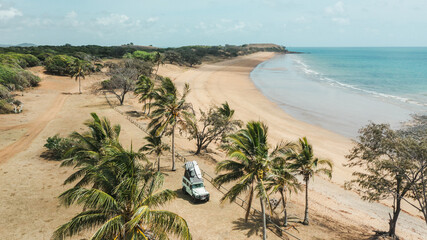 Camping on a beach under palm trees and a land rover defender
