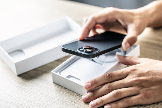 A customer in a smartphone store opens a box with a new phone