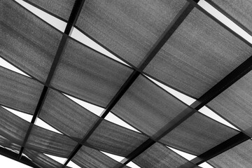 Terrace roof made of strips of fabric on wooden framework is under the sky