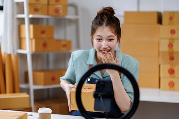vlogger, blogger small SME business asian beautiful woman using mobile phone video call for sell products online live stream, show product present detail at home office, entrepreneur ecommerce
