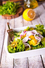 Bright juicy salad with yellow cherry tomatoes and aromatic basil leaves in bowl.