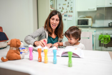 Fototapeta premium A woman and a child are sitting at a table with a book