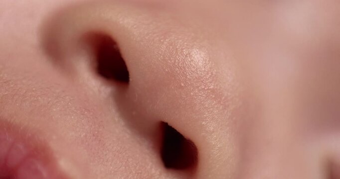 Close-up shot of the gaping mouth, upper lip, and the opening of a newborn infant's nostrils.