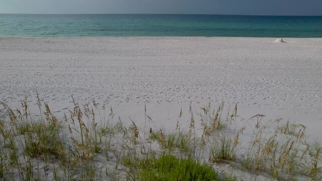 Fly over on sand dunes on white sand beach in Florida on a sunny day with clear waters