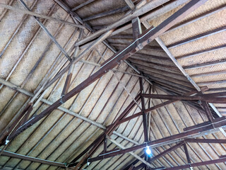 Looking up from below, the intricate wooden beams of the roof form a precise, geometric pattern. The warm, natural tones of the wood contrast with the shadows, creating a sense of depth and craftsmans