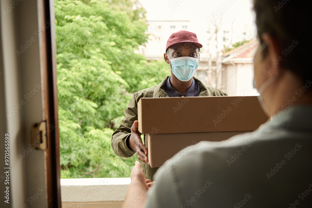 Wall mural African courier in a mask giving packages to a customer