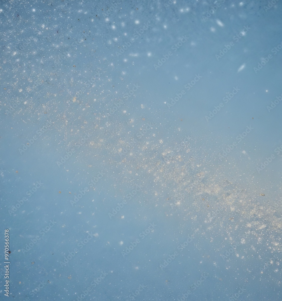 Poster a blurred, abstract representation of a galaxy or starry night sky, with a gradient of blue tones and small white specks or particles scattered throughout.