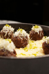Italian meatballs with cheese sauce in frying pan.