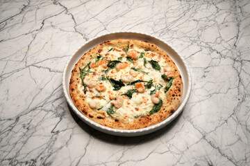 Italian shrimp pizza. Pizza with shrimps, herbs and cheese on a white plate
