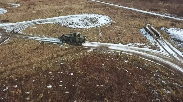 AERIAL VIEW: Armored Ukrainian personnel carrier training ground performs exercises to pass obstacles. Military equipment training ground in Ukraine. Training track at a military training ground