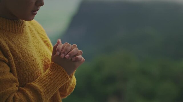 Young woman praying for blessing from god. Christian concept. Hope, goodness and faith. Prayer conversation. Talking to god in spirit on mountain with nature view.