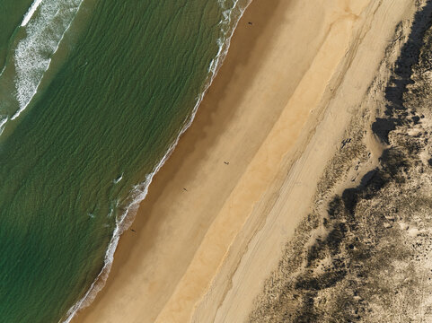 Aerial image of ocean waves crashing into very large empty beach. Cap de l'Homy, France