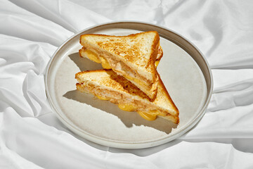 A classic grilled cheese sandwich with melted cheese and toasted bread. The sandwich is cut into triangles and served on a white plate.