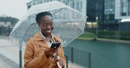 Happy, black woman and phone with umbrella for rain weather, communication and social media of security. Smile, female person and mobile for texting, search location and taxi app of travel outdoor © David/peopleimages.com