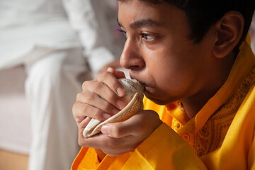 An Indian boy blows the sacred 'conch' during the Hindu festival of 'Krishna Janmashtami', performing a traditional religious ritual.