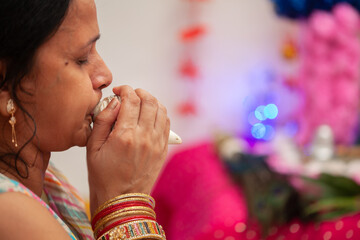 An Indian woman blows the sacred 'conch' during the Hindu festival of 'Krishna Janmashtami',...