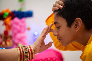 An Indian woman applying tilak on forehead after completing a Hindu pooja, symbolizing devotion and blessing rituals.