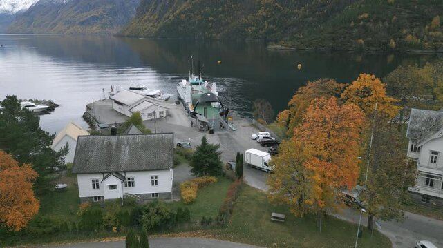 Ferry unloading cars at Hellesylt, Norway surrounded by autumn trees and calm fjord waters