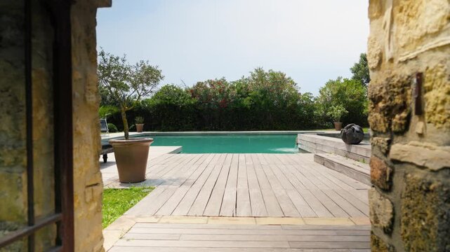 Slow dolly shot through a stone gate revealing a private tropical swimming pool