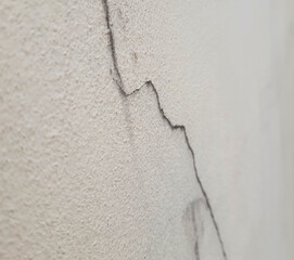 The cracks on the cream-colored concrete wall are long lines like mountains. The surface of the concrete is clearly visible, giving an unusual feeling.