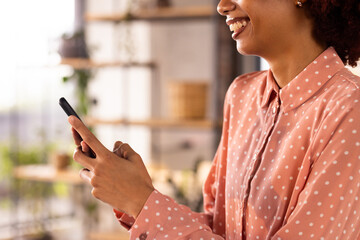 At office, Using smartphone, woman smiling and typing message in creative workspace