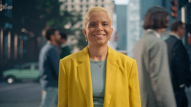 Portrait of a Confident African Woman in a Bright Yellow Blazer Standing on a Busy Urban City Street, Posing for Camera, Smiling. Diverse People Moving Around Her on Their Way to Work