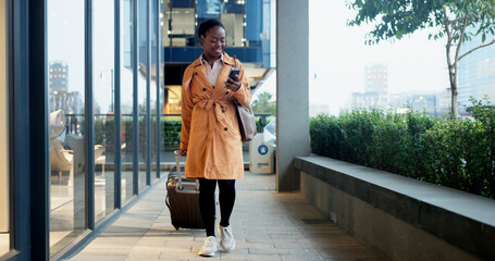 Phone, night and suitcase with black woman in city for communication, travel or technology. Chief automation office, ai engineer and rpa software with person and mobile for hackathon expo or seminar