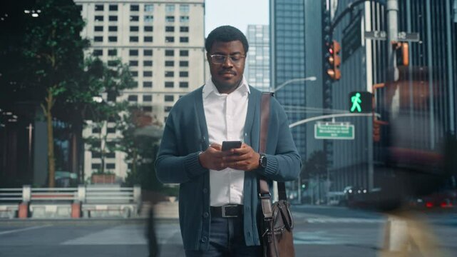Timelapse Footage of an African American Man Standing and Using Smartphone on Busy City Street, Surrounded by Commuting Blurred Motion of Pedestrians. Portrait of a Black Male in Glasses