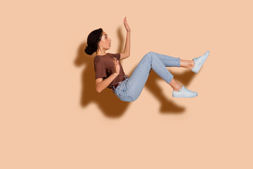 Photo of worried nervous cute woman wear brown stylish clothes fly air panic stupor isolated on...