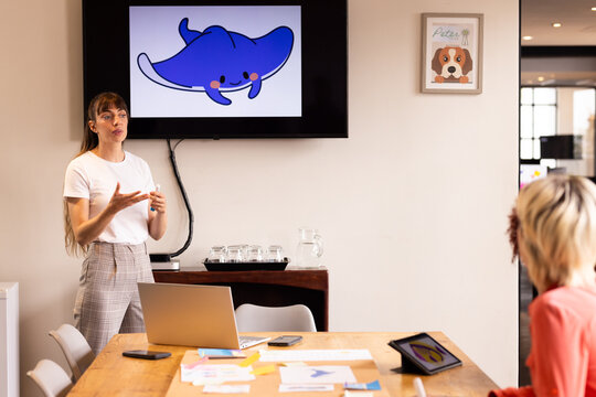 Presenting creative ideas, woman showing cartoon stingray on screen in office meeting