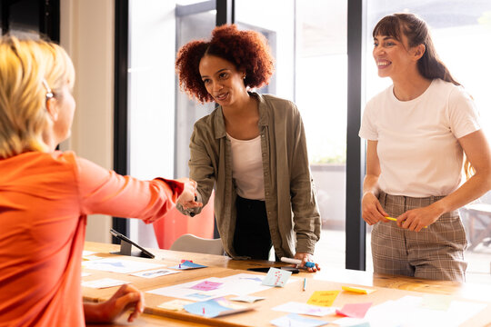 Shaking hands, multiracial businesswomen collaborating on creative project in modern office