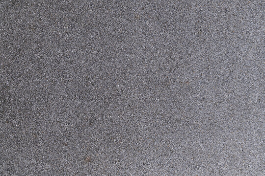A rough, granular grey surface, reminiscent of coarse sandpaper or asphalt texture