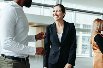 Businesswoman laughing and networking at a conference in an office setting